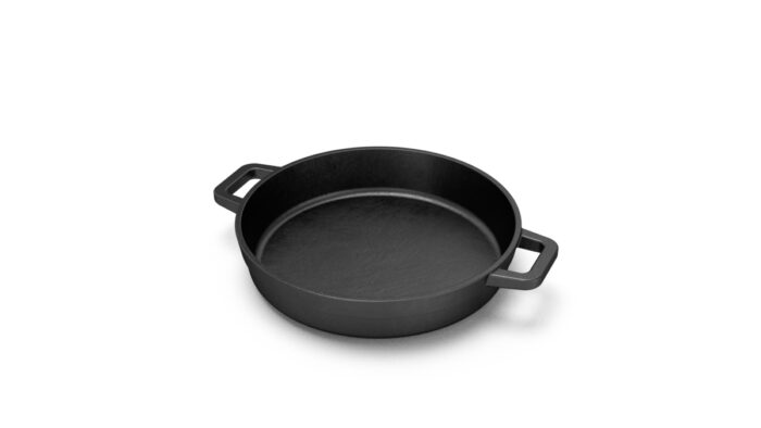 The Bastard litoželezna ponev z dvema ročajema, primerna za uporabo na kamado žaru, prikazana s pripravljeno jedjo.